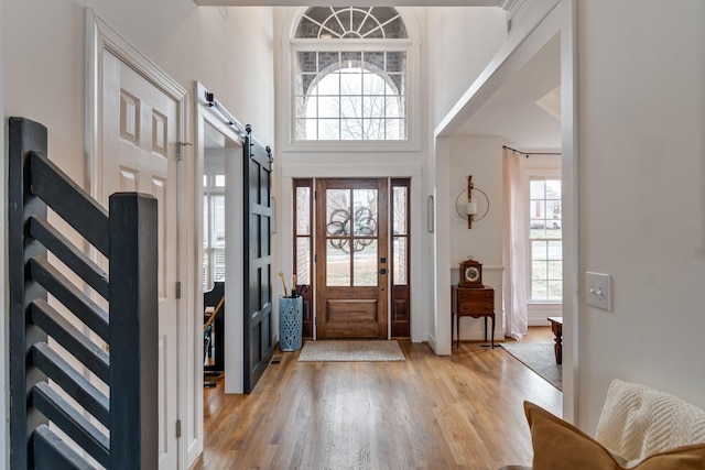 entryway with a high ceiling, a barn door, and light wood-type flooring