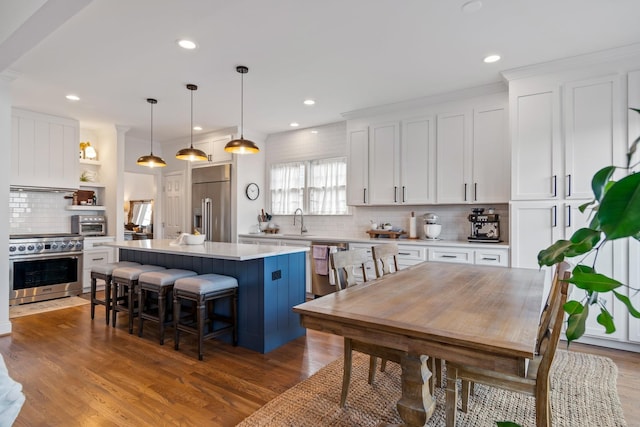 kitchen with pendant lighting, white cabinetry, a center island, and premium appliances