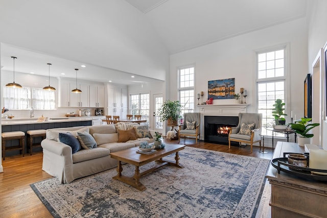 living room with high vaulted ceiling, sink, and light wood-type flooring