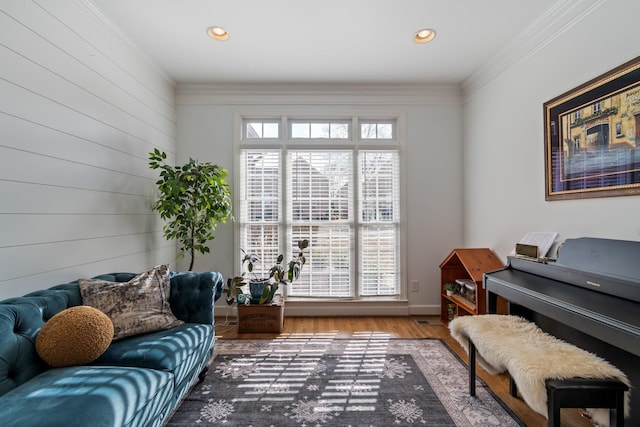 living area with hardwood / wood-style flooring, a wealth of natural light, and ornamental molding