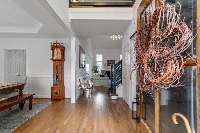 foyer with ornamental molding, hardwood / wood-style floors, and a notable chandelier