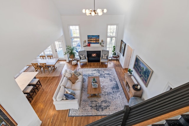 living room featuring light hardwood / wood-style floors, a towering ceiling, and a notable chandelier