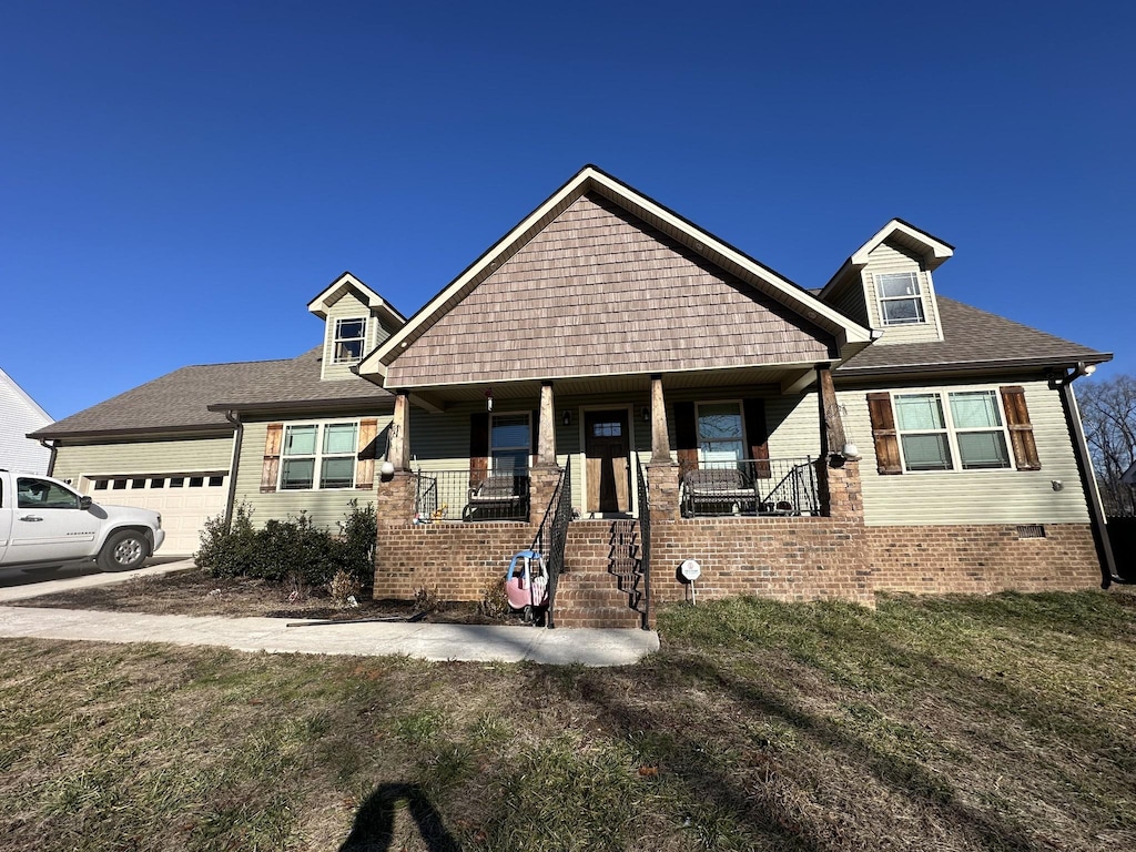 craftsman house with covered porch, a front yard, and a garage