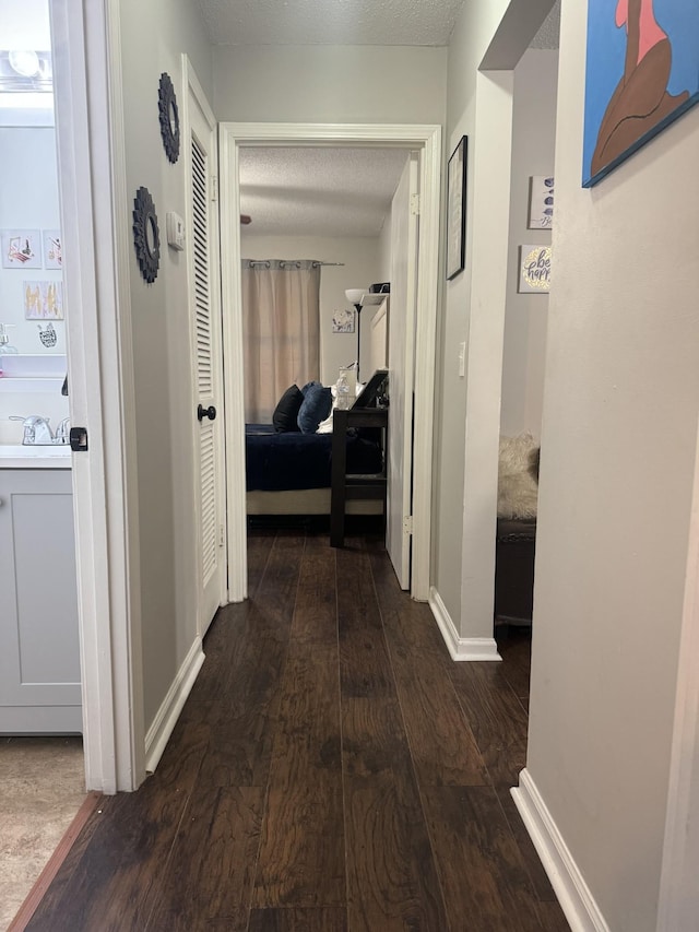 hall featuring dark wood-type flooring and a textured ceiling