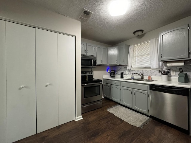 kitchen featuring sink, gray cabinets, a textured ceiling, and appliances with stainless steel finishes