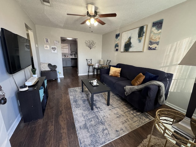 living room with ceiling fan, dark wood-type flooring, and a textured ceiling