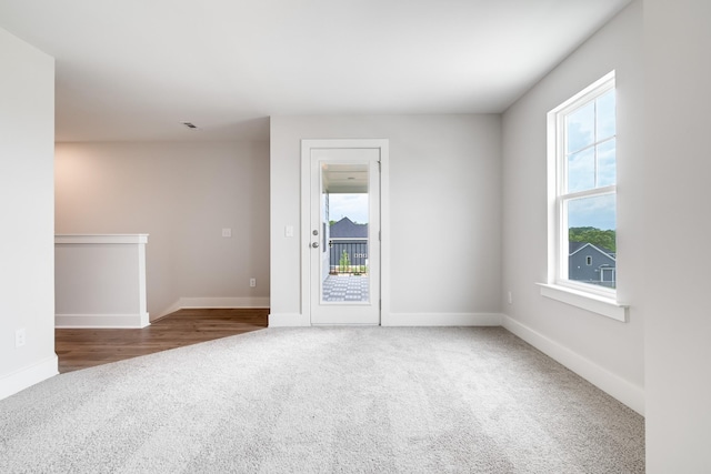 spare room featuring a wealth of natural light and dark colored carpet