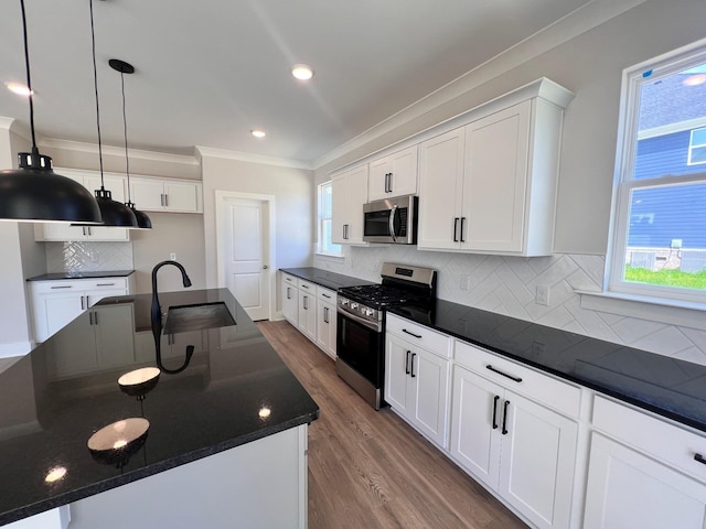 kitchen featuring backsplash, white cabinetry, appliances with stainless steel finishes, and a center island with sink