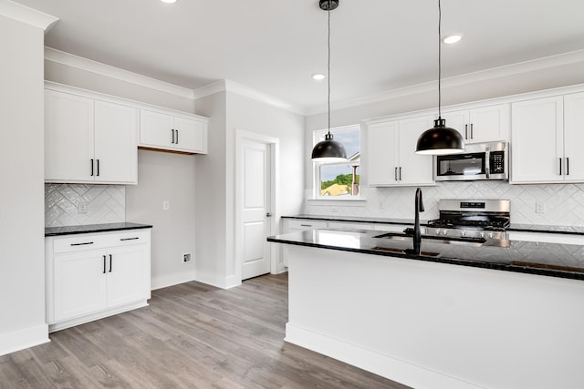 kitchen with light hardwood / wood-style floors, stainless steel appliances, white cabinetry, and pendant lighting