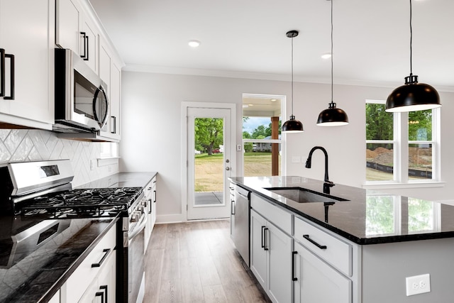 kitchen with sink, white cabinets, stainless steel appliances, and a kitchen island with sink