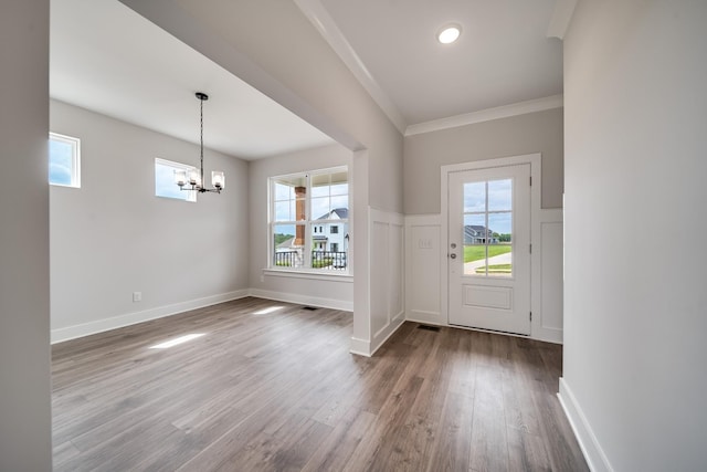 entrance foyer with dark hardwood / wood-style flooring, crown molding, a notable chandelier, and a healthy amount of sunlight