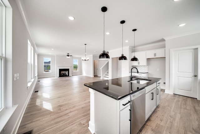 kitchen featuring stainless steel dishwasher, sink, white cabinetry, a kitchen island with sink, and decorative backsplash