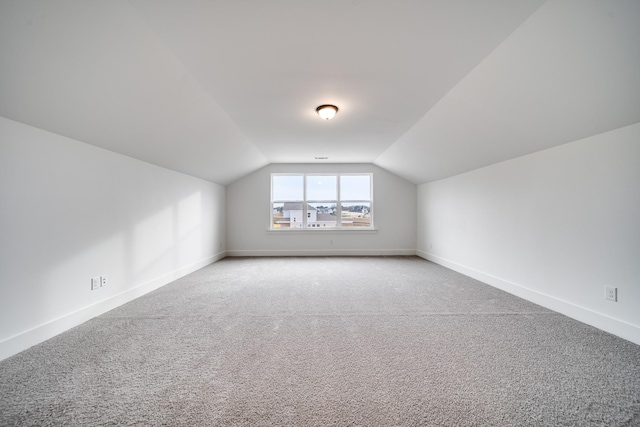 additional living space featuring carpet flooring and lofted ceiling