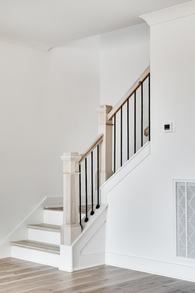 stairs with crown molding and hardwood / wood-style floors