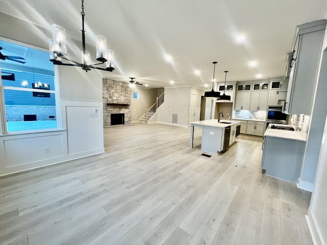 kitchen with a kitchen island with sink, a kitchen breakfast bar, sink, decorative light fixtures, and ceiling fan with notable chandelier