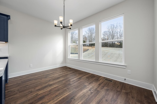 unfurnished dining area with an inviting chandelier and dark hardwood / wood-style flooring