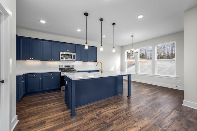 kitchen featuring appliances with stainless steel finishes, a kitchen bar, dark wood-type flooring, an island with sink, and blue cabinets