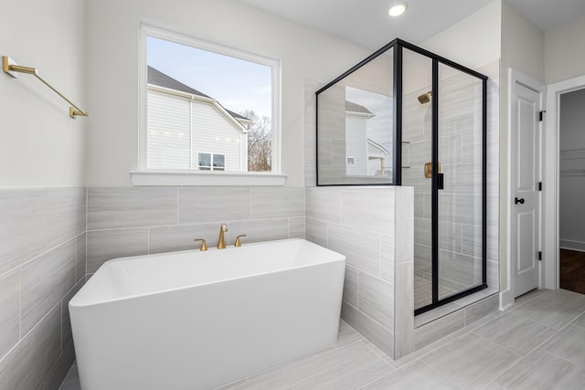 bathroom featuring plus walk in shower, tile patterned flooring, and tile walls