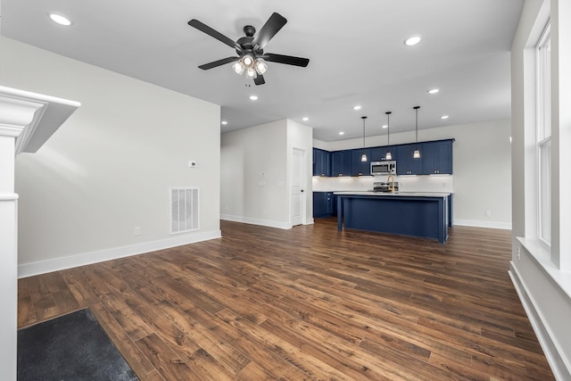 unfurnished living room with ceiling fan and dark wood-type flooring