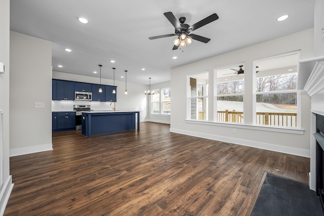 unfurnished living room with sink, ceiling fan with notable chandelier, and dark wood-type flooring