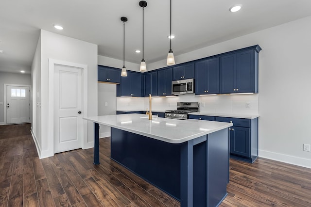 kitchen featuring blue cabinetry, dark wood-type flooring, an island with sink, stainless steel appliances, and a breakfast bar area