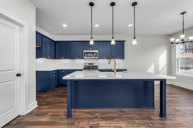 kitchen featuring dark hardwood / wood-style flooring, pendant lighting, a center island with sink, and stainless steel appliances