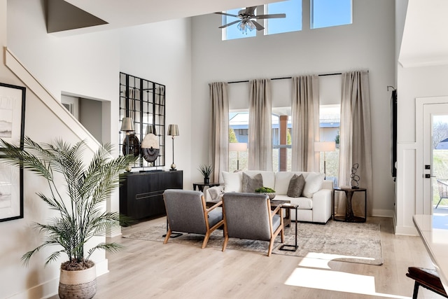 living room with a high ceiling, ceiling fan, and light hardwood / wood-style floors