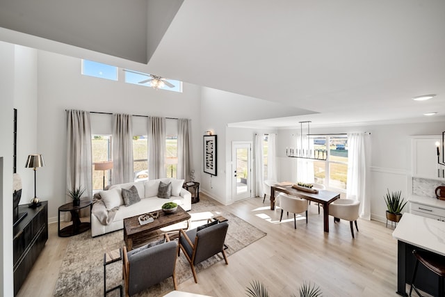 living room with ceiling fan with notable chandelier and light hardwood / wood-style floors