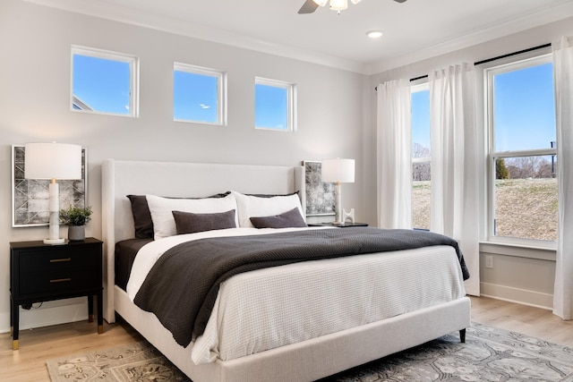 bedroom with ceiling fan, ornamental molding, light hardwood / wood-style floors, and multiple windows