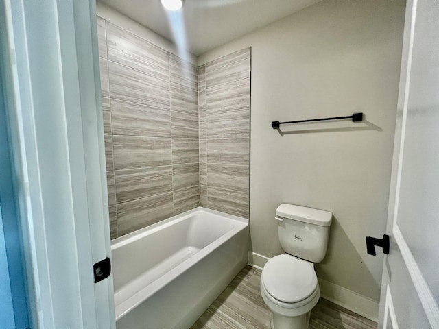 bathroom featuring tiled shower / bath combo and toilet