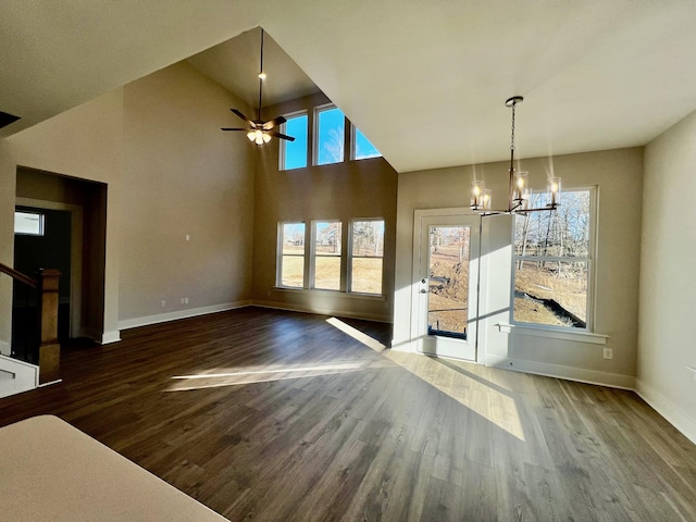 unfurnished dining area featuring dark wood-type flooring, lofted ceiling, and ceiling fan with notable chandelier