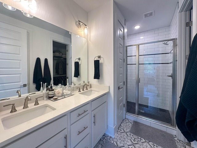 bathroom with a shower with door, tile patterned floors, and vanity