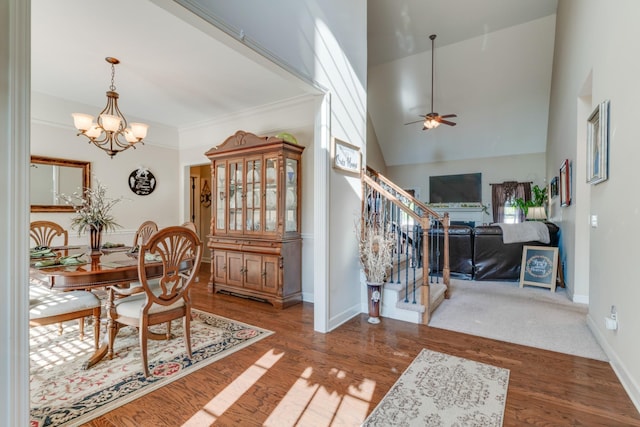 dining space featuring high vaulted ceiling, wood-type flooring, and ceiling fan with notable chandelier