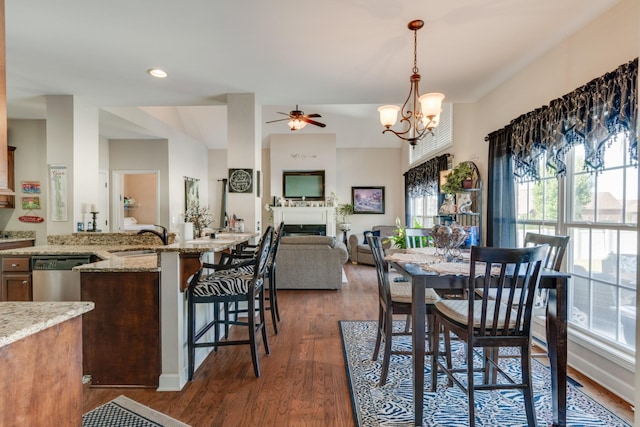 dining area with ceiling fan with notable chandelier, sink, and dark hardwood / wood-style flooring