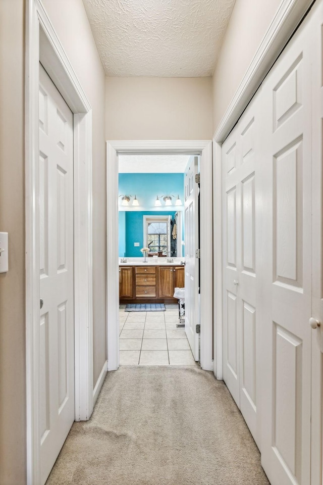 corridor with a textured ceiling and light carpet