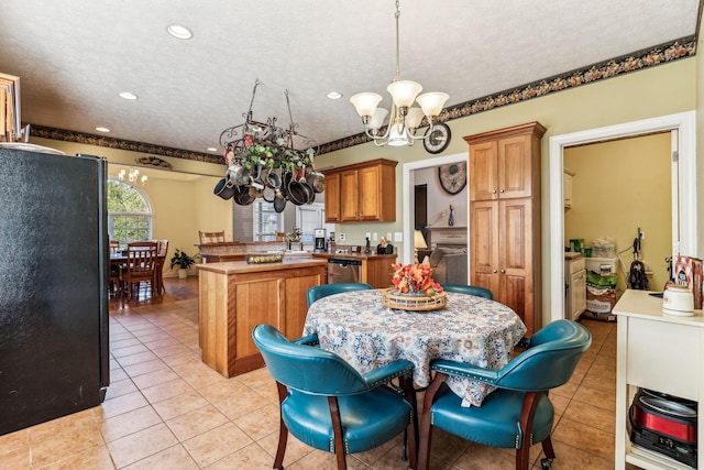 kitchen featuring a textured ceiling, dishwasher, a chandelier, light tile patterned floors, and black fridge