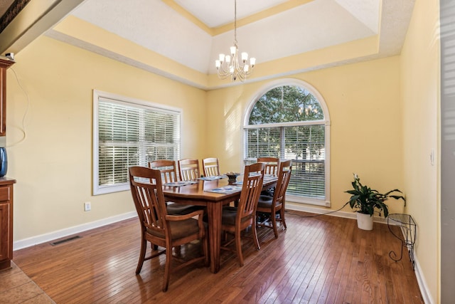 dining space featuring an inviting chandelier, dark hardwood / wood-style floors, and a tray ceiling