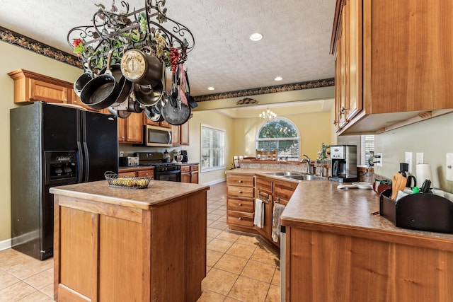 kitchen with a textured ceiling, black appliances, a center island, sink, and light tile patterned floors