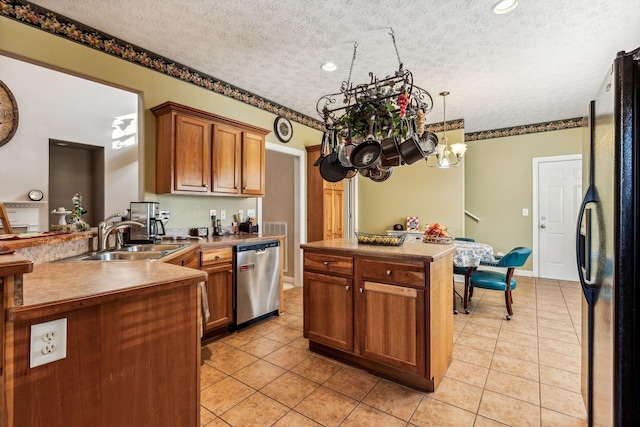 kitchen featuring black refrigerator, a textured ceiling, stainless steel dishwasher, sink, and light tile patterned flooring