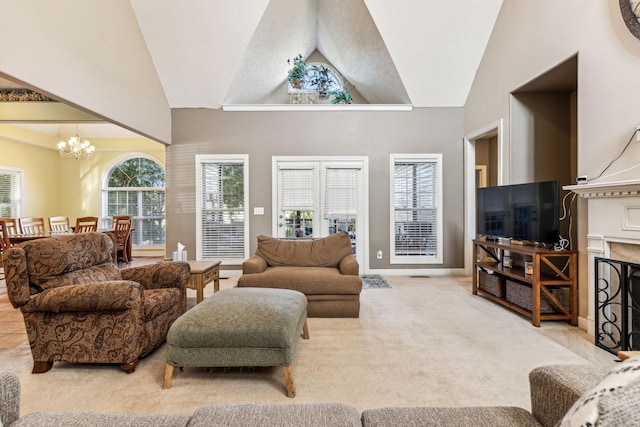 living room with light carpet, a chandelier, high vaulted ceiling, and a high end fireplace