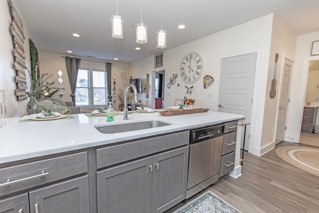 kitchen featuring stainless steel dishwasher, pendant lighting, sink, hardwood / wood-style flooring, and gray cabinetry