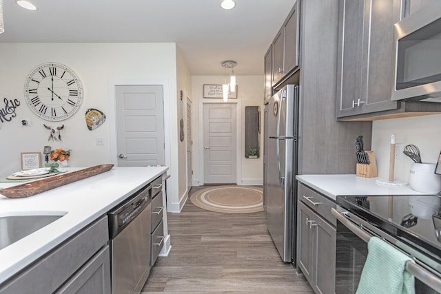 kitchen featuring hardwood / wood-style floors, hanging light fixtures, and appliances with stainless steel finishes