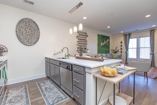 kitchen with dishwasher, hanging light fixtures, sink, dark wood-type flooring, and a kitchen bar