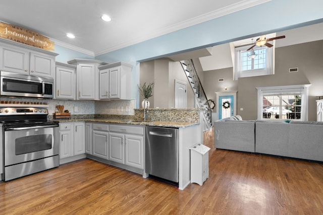 kitchen featuring appliances with stainless steel finishes, white cabinetry, decorative backsplash, sink, and light hardwood / wood-style flooring