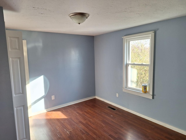 empty room featuring dark wood-type flooring and a textured ceiling