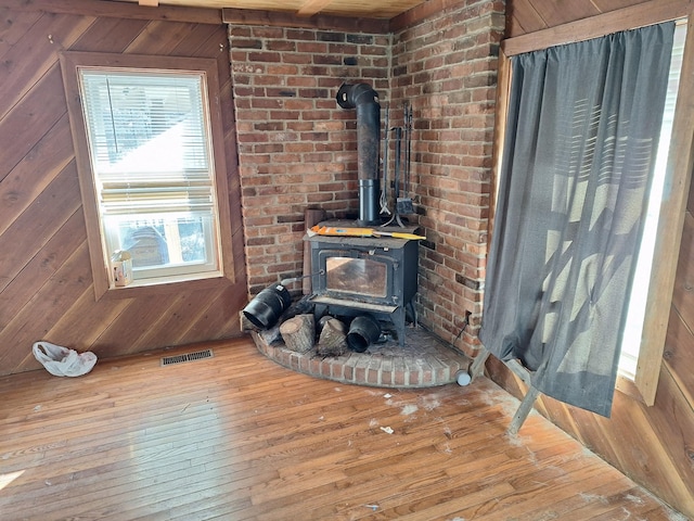 interior details featuring a wood stove, wood-type flooring, and wooden walls