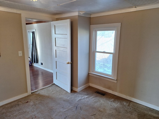 carpeted spare room featuring crown molding