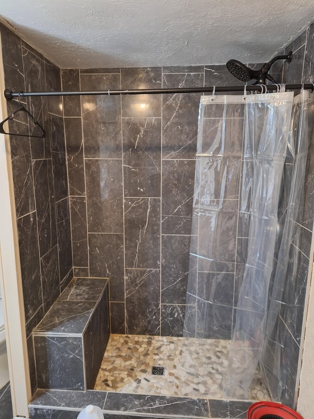 bathroom with a tile shower, toilet, and a textured ceiling