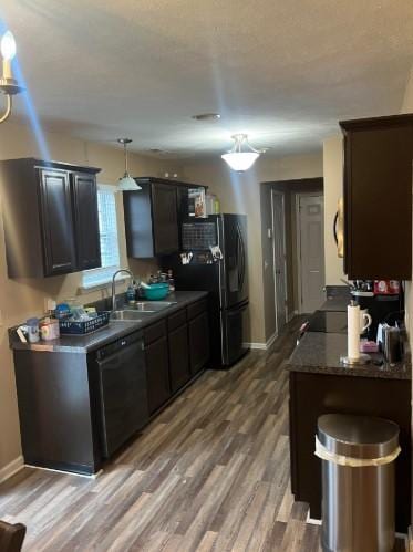 kitchen featuring sink, hardwood / wood-style floors, dark brown cabinetry, and black appliances