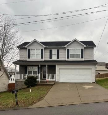 view of property featuring a garage, a front lawn, and covered porch